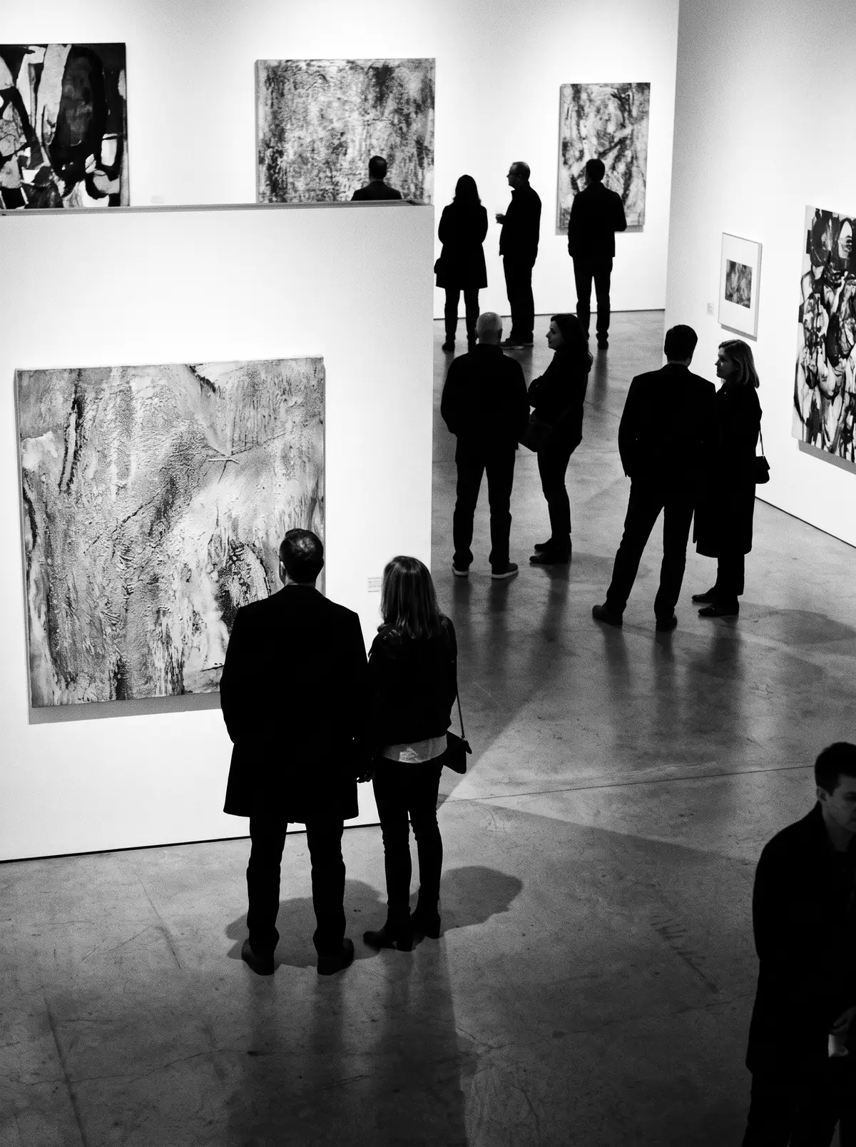 A gallery night, figures among the art, black and white